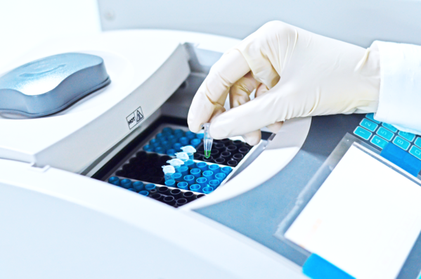 Scientist putting a PCR tube into PCR test machine